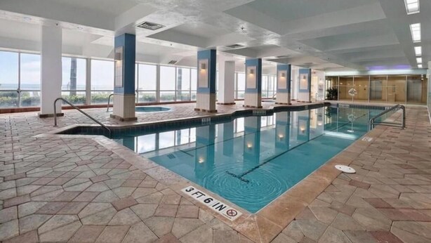 An indoor swimming pool with clear water, a 3ft 6in depth marking, and a view of the sky through large windows.