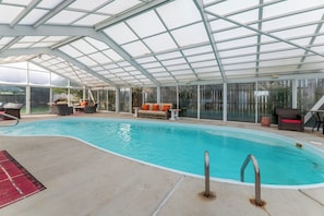 A covered swimming pool with lounge chairs and a glass ceiling. - The Sea Spirit-KDH MP 7, Oceanside, Elevator, Pool, Hot Tub, Pets OK, YR Flex Stays (Kill Devil Hills)