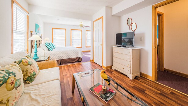 Ein Schlafzimmer mit einem Bett, Nachttischen, einem Schminktisch und einem Fernseher sowie einer Tür.