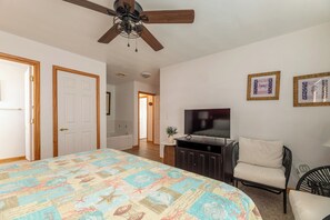 A bedroom with a bed, a television, a chair, and a ceiling fan. - Captains Choice-KDH MP 7, Oceanside, Pool, Hot Tub, Pets OK, YR Flex Stays (Kill Devil Hills)