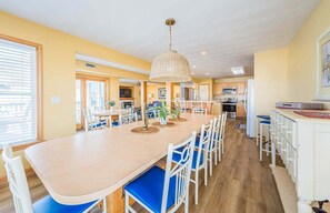 A spacious kitchen with a central island, white cabinetry, and blue chairs. - Captains Choice-KDH MP 7, Oceanside, Pool, Hot Tub, Pets OK, YR Flex Stays (Kill Devil Hills)