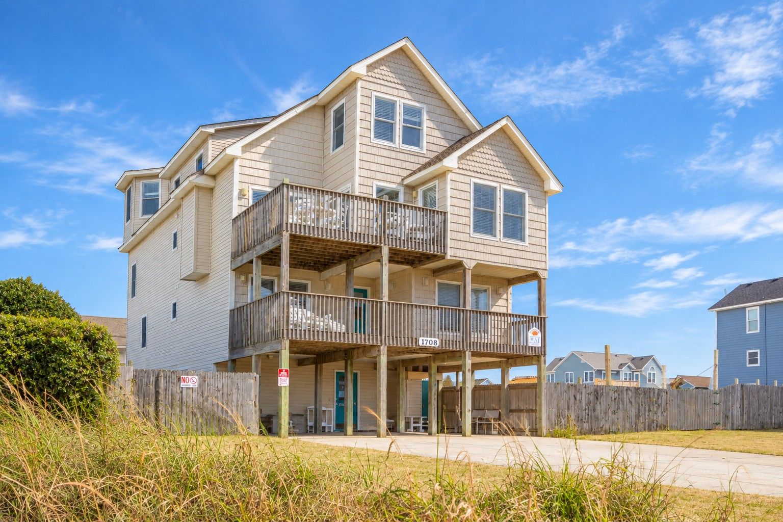 A two-story residential building with a balcony on the upper floor, a visible porch area, and a clear sky.