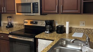 Una cucina con piani in granito, elettrodomestici in acciaio inossidabile e mobili in legno.