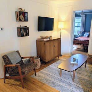 A living room with a television, a wooden cabinet, a patterned rug, and a sofa.