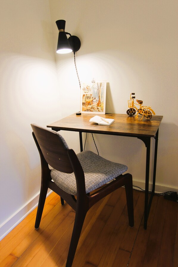 A small wooden desk with a chair, a lamp, a framed picture, and a toy bicycle.