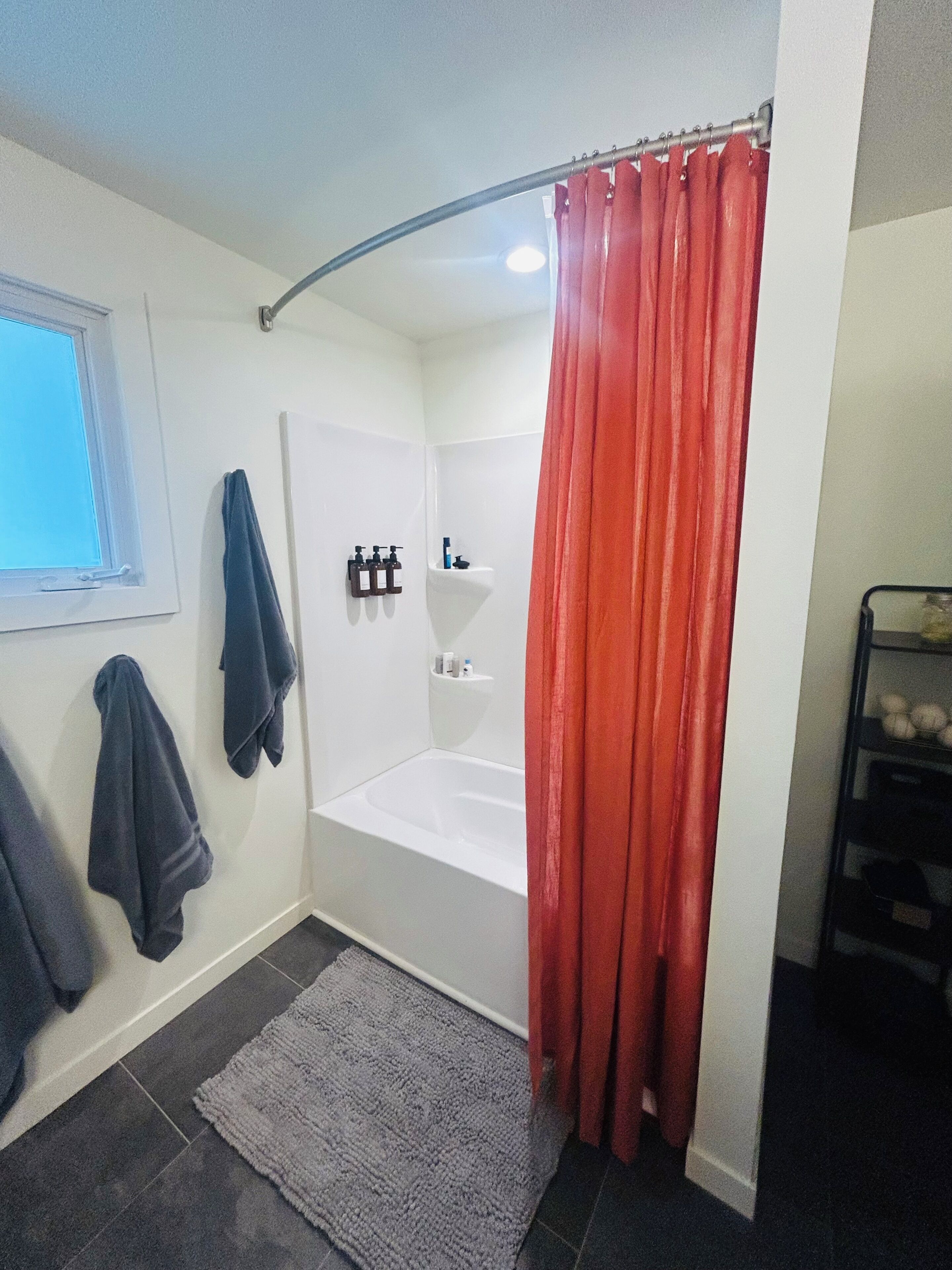 Une salle de bain équipée d’une douche, d’une baignoire, d’un porte-serviettes et d’une étagère pour les articles de toilette.