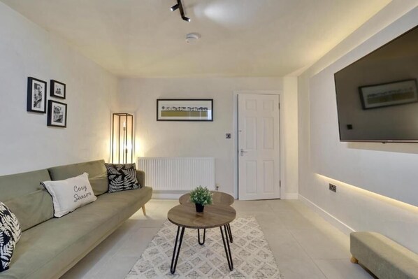 A modern living room with a sofa, a coffee table, and a television mounted on the wall.