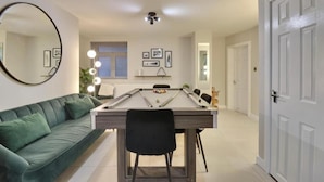A room with a pool table, a green sofa, and a dining table with chairs. - Southsea Luxury Apartment with Hot tub   (Portsmouth)
