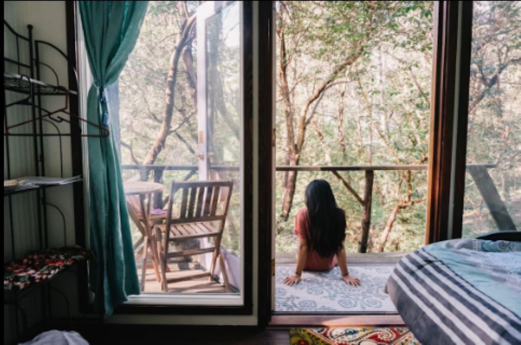 Una habitación con un ventanal grande, una cama, una silla y una mesita.
