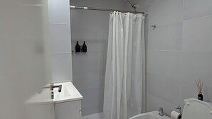 Et moderne badeværelse med brusebad, toilet, bidet og håndvask.