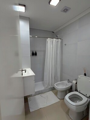Ein modernes Badezimmer mit Dusche, Toilette, Bidet und Waschbecken.