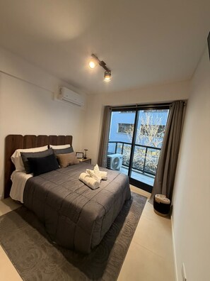 A bedroom with a large bed, a ceiling light, an air conditioning unit, and a view of the outside through a window. - Comfortable and Elegant Vitraux Recoleta (Buenos Aires)