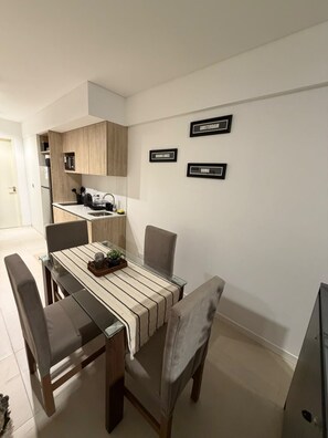 Una cocina moderna con armarios de madera, una mesa de comedor con sillas y un refrigerador.