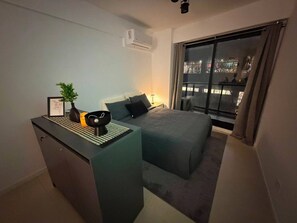 Ein modernes Schlafzimmer mit Bett, Nachttisch und Blick auf die beleuchtete Stadt bei Nacht.