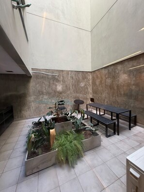 A spacious indoor area with a modern design, featuring a seating arrangement with benches and a table, surrounded by potted plants and a tiled floor. - Comfortable and Elegant Vitraux Recoleta (Buenos Aires)