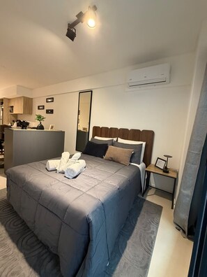 A modern hotel room with a large bed, a bedside table, a mirror, and a kitchenette area. - Comfortable and Elegant Vitraux Recoleta (Buenos Aires)