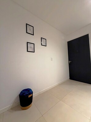 Ein Zimmer mit Fliesenboden, einer schwarzen Tür und drei gerahmten Bildern an der Wand.