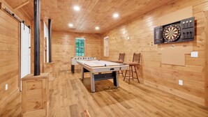 A room with a foosball table, dartboard, and wooden walls. - Willow Ridge Hideaway  Fully Renovated Log Cabin · 10 Min to Boone · Hot Tub (Vilas)