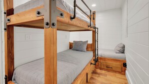 A bunk bed room with wooden frames, a small desk, and a single bed with a grey striped bedspread. - Willow Ridge Hideaway  Fully Renovated Log Cabin · 10 Min to Boone · Hot Tub (Vilas)