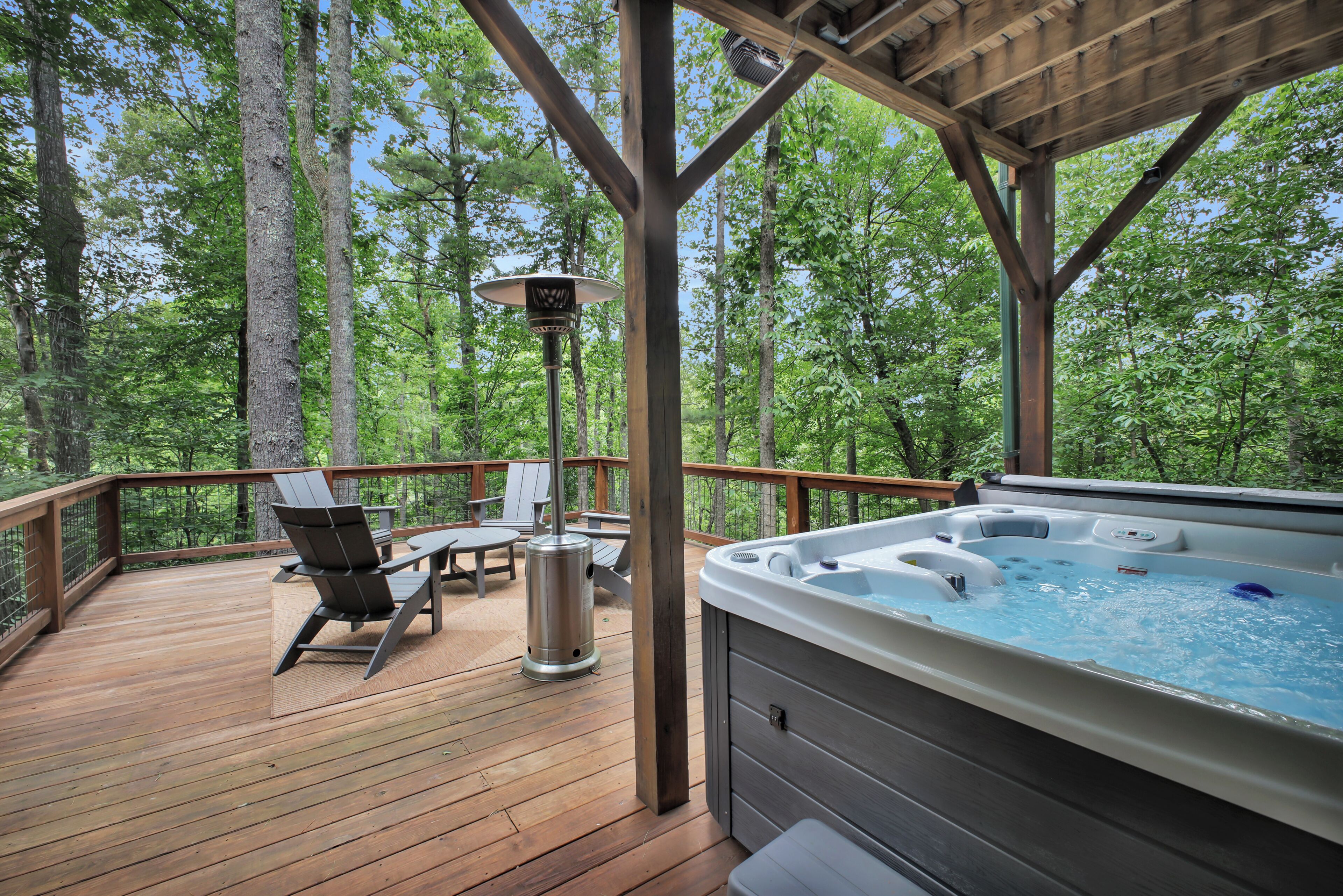 Eine Holzterrasse mit Whirlpool, Liegestühlen und einem Tisch.