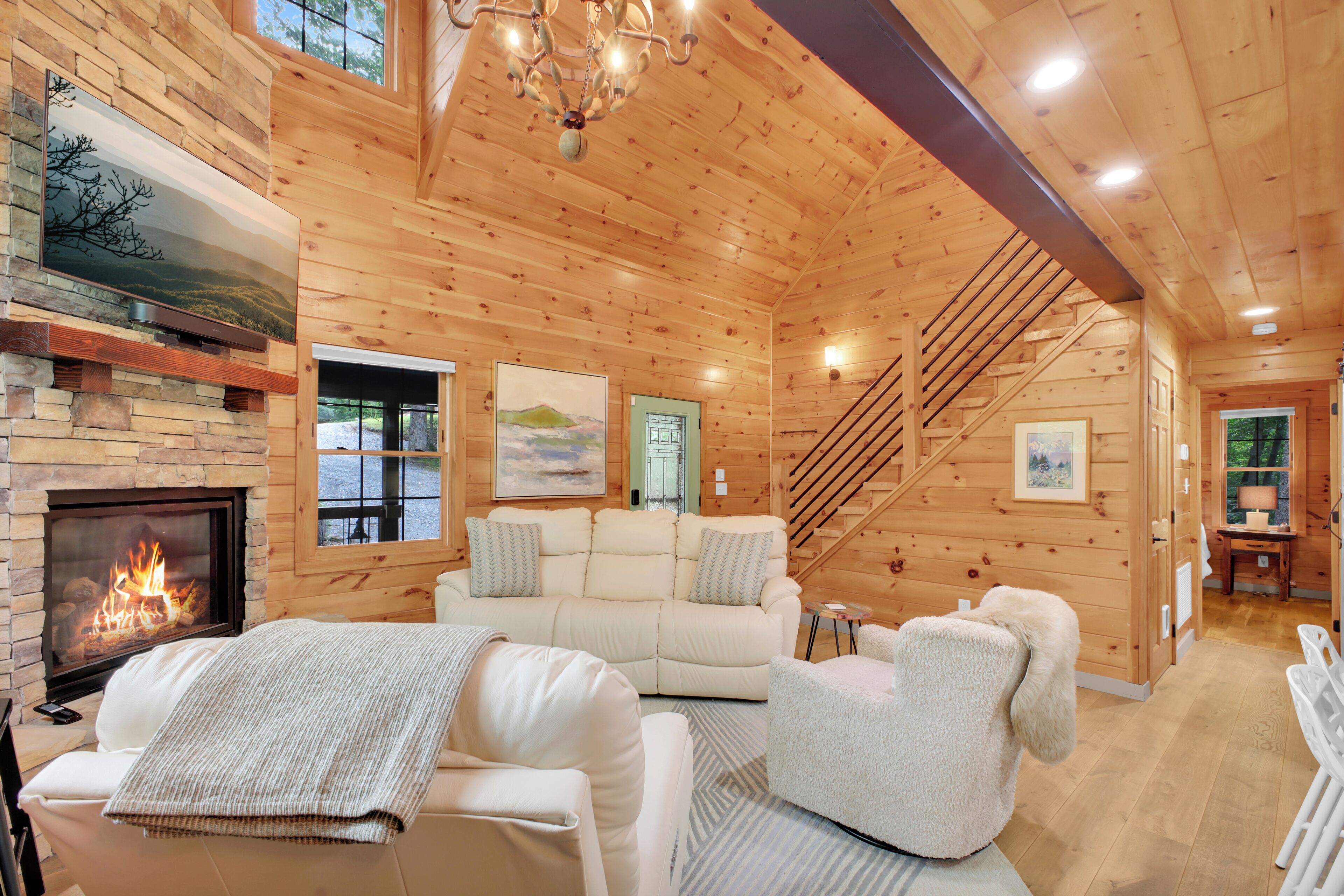 Interior acogedor de una cabaña con chimenea, asientos cómodos y una escalera.