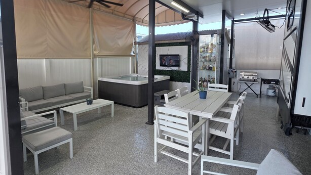 A covered outdoor seating area with a sofa, tables, and a hot tub. - 2-bedroom campground in peaceful Key Largo with AC comfort. (Key Largo)