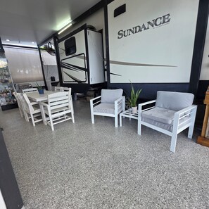 Ein Zimmer mit weißen Möbeln, einer Wand mit 'SUNDANCE'-Branding und einem Grillbereich.