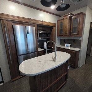 A kitchen with a stainless steel refrigerator, a microwave, and wooden cabinets. - 2-bedroom campground in peaceful Key Largo with AC comfort. (Key Largo)