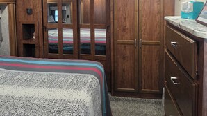 A bedroom with a bed, wooden wardrobe, and a bathroom with a mirror and towel dispenser. - 2-bedroom campground in peaceful Key Largo with AC comfort. (Key Largo)