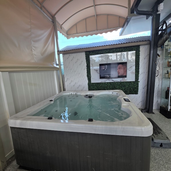 A hot tub with a television screen mounted on the wall above it.