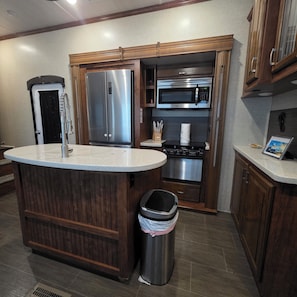 A kitchen with a stainless steel refrigerator, a microwave, an oven, and a sink.