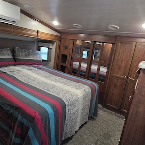 A bedroom with a bed, wooden wardrobe, and a window.
