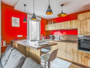 A modern kitchen with wooden cabinets, a central island, and pendant lighting. - Appartement Ollier - Welkeys (Villeurbanne)