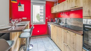 Une cuisine moderne avec des murs rouges, des meubles en bois et un coin repas équipé de tabourets de bar.