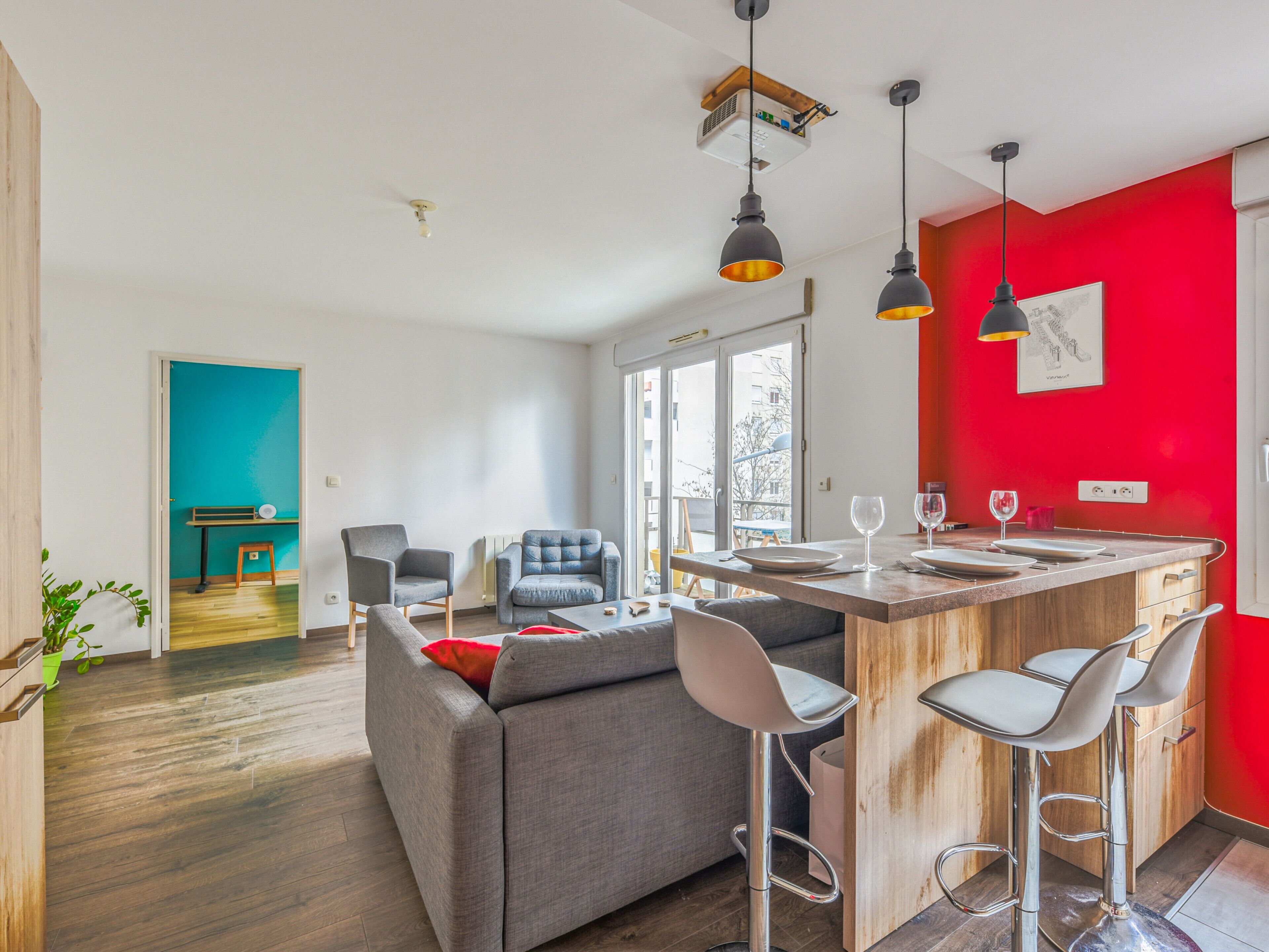 A modern kitchen with a red accent wall, a bar area, and a seating area with a sofa and chairs.