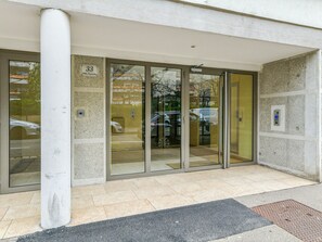 A building entrance with a glass door, a white pillar, and a sign indicating the address. - Appartement Ollier - Welkeys (Villeurbanne)