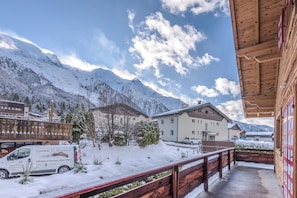 A snowy mountain landscape with buildings and a wooden balcony. - Chalet Vue des Bossons - Welkeys (Chamonix-Mont-Blanc)