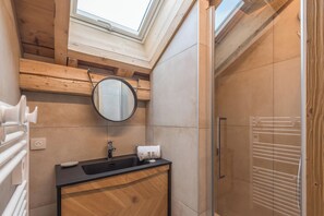 Un baño moderno con tragaluz, tocador de madera y cabina de ducha de vidrio.