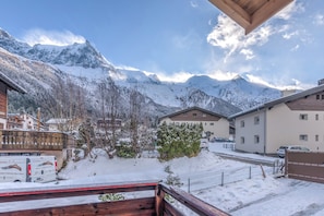 A snow-covered mountain landscape with buildings and a wooden deck. - Chalet Vue des Bossons - Welkeys (Chamonix-Mont-Blanc)