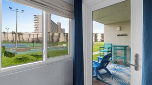 A view from a balcony with a tennis court and buildings in the background. - Ground Floor Condo | 2 King Suites | Beach (Panama City Beach)