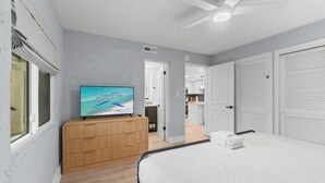 A bedroom with a bed, a television on a dresser, and a ceiling fan. - Ground Floor Condo | 2 King Suites | Beach (Panama City Beach)