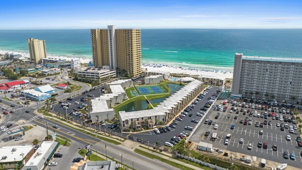 A coastal hotel with multiple high-rise buildings, a parking lot, and a beach area. - Ground Floor Condo | 2 King Suites | Beach (Panama City Beach)