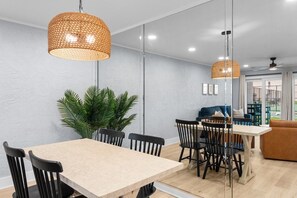A modern dining area with a large table, black chairs, and woven pendant lights. - Ground Floor Condo | 2 King Suites | Beach (Panama City Beach)