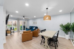 Ein großzügiger Wohnbereich mit Esstisch, Sofas und Deckenventilator.