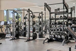 A gym with various exercise equipment, weight racks, and cardio machines.