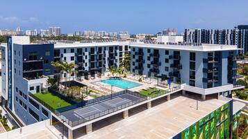 A modern building with a rooftop pool, multiple balconies, and a clear view of the surrounding cityscape.