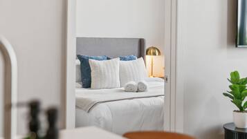 A hotel room with a bed, a bedside lamp, and a potted plant.