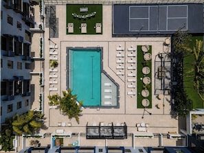 An aerial view of a hotel with a swimming pool, sun loungers, a tennis court, and a landscaped garden. - King Bed | Gym |Resort Style Pool | Minutes to Beach | Pet Friendly |Pickle Ball (Fort Lauderdale)