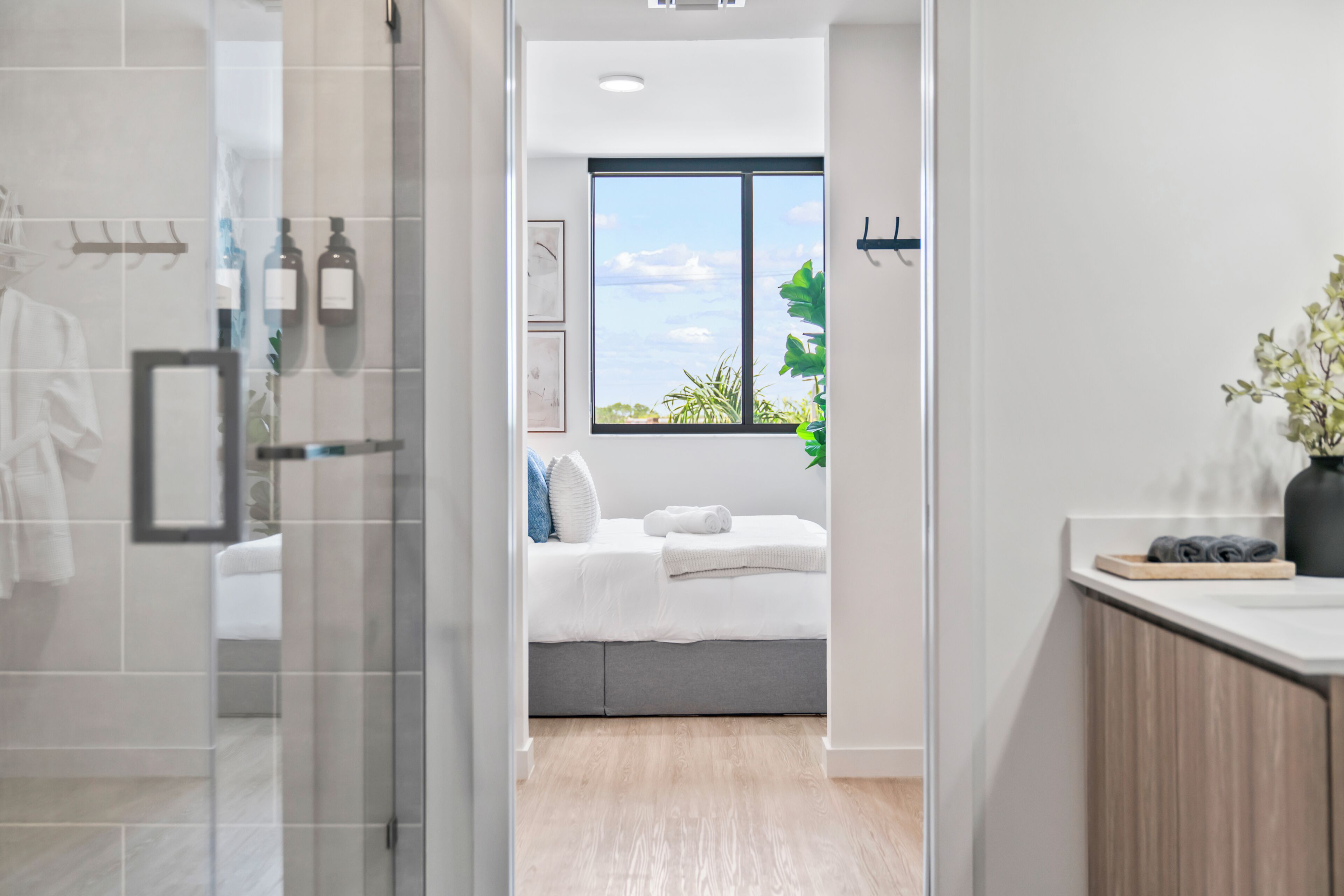 Een moderne badkamer met een glazen douchecabine, een zichtbare handdoekhouder en een groot raam met uitzicht op groen.