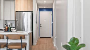 Una cocina moderna con refrigerador de acero inoxidable, un lavamanos y taburetes de bar.